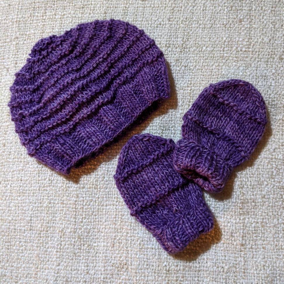 A purple baby bonnet and mits